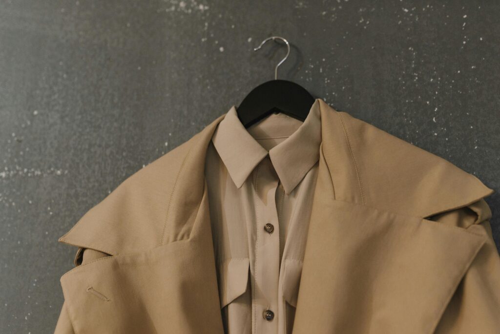 Stylish beige coat and shirt on hanger, perfect for autumn fashion.