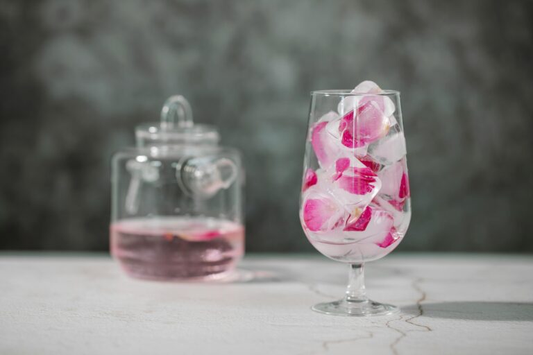 Delightful glass of rose water with ice and petals, offering refreshing aroma.